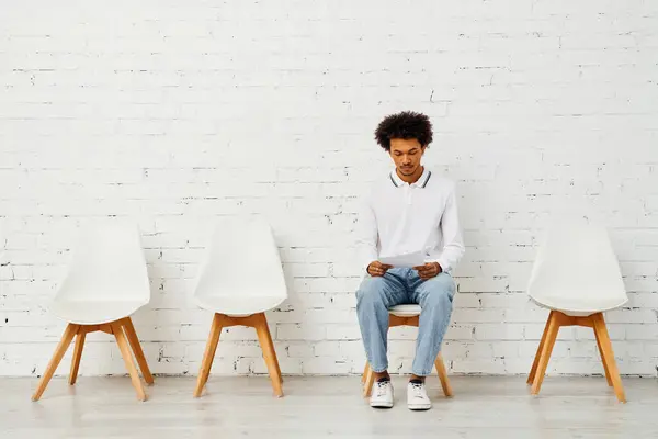 Homem cercado por cadeiras brancas em uma exposição artística de solidão. — Fotografia de Stock