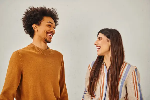 Man and woman laugh happily in front of plain backdrop. — Stock Photo