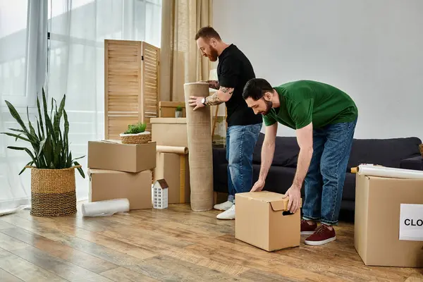 Two men, a gay couple, are moving boxes in their living room in preparation for their new life together — Stock Photo