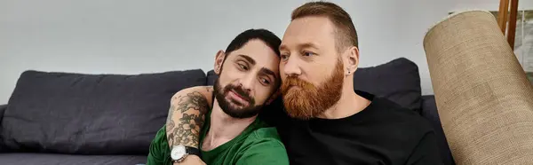 A gay couple in love sits closely on a couch, symbolizing a fresh start in their new home. — Stock Photo