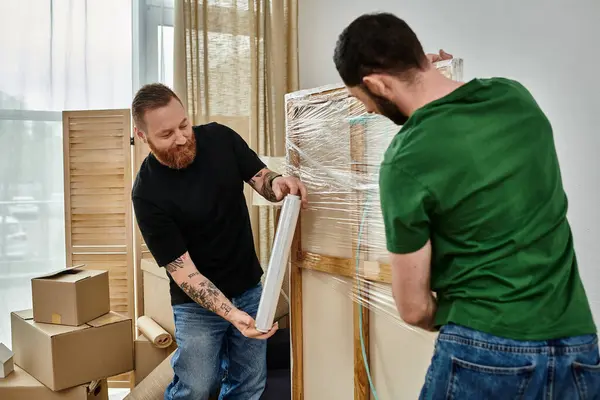 A gay couple in a room filled with moving boxes, starting a new life together — Stock Photo