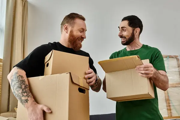 Um casal gay segura caixas em sua nova casa, simbolizando um novo começo cheio de amor e possibilidade. — Fotografia de Stock