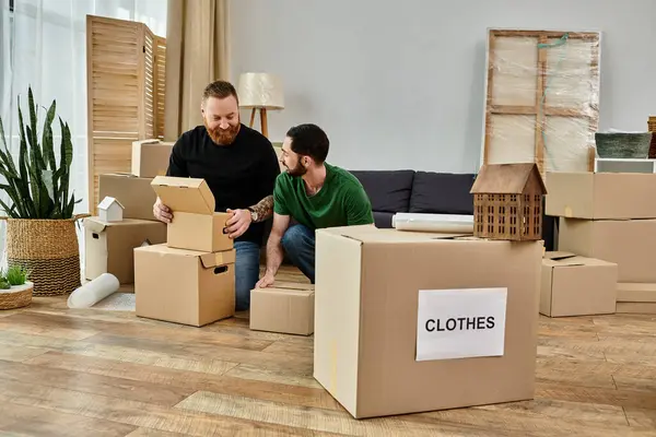 A man and a boy sit comfortably on cardboard boxes, sharing a moment of bonding and connection amidst a new chapter in their lives. — Stock Photo