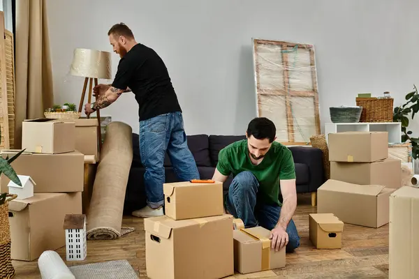 Dois homens, um casal gay apaixonado, movendo caixas em uma sala de estar de sua nova casa, marcando o início de um novo capítulo. — Fotografia de Stock