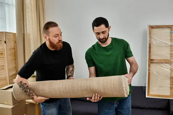 A loving gay couple in their new home, surrounded by moving boxes, excitedly standing next to each other. — Stock Photo