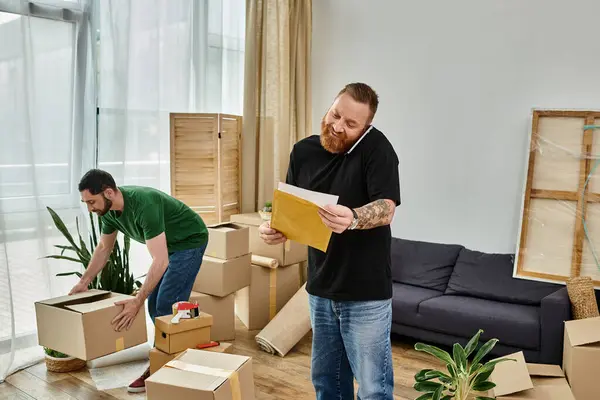 Um casal gay fica em sua nova sala de estar cheia de caixas, embarcando em um novo começo juntos. — Fotografia de Stock