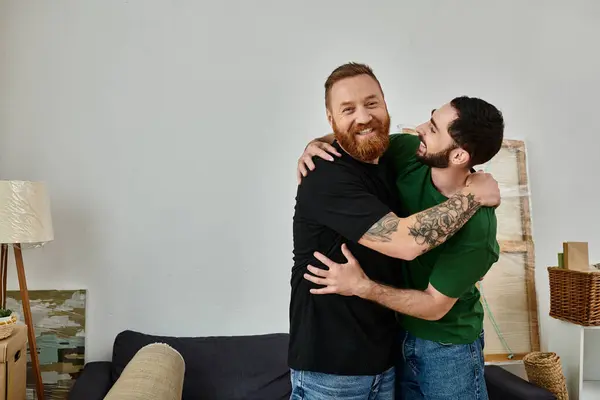 Deux hommes s'embrassent dans le salon, célébrant le début d'une nouvelle vie ensemble. — Photo de stock
