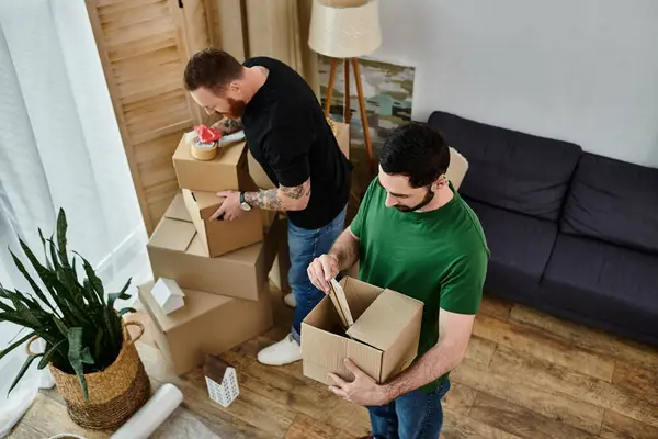 Dois homens desembalar caixas em sua nova sala de estar, cheio de amor e emoção para o seu novo começo juntos. — Fotografia de Stock