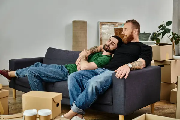 Gay coppia in amore seduto su divano circondato da imballato scatole inizio nuovo capitolo nella loro vita viaggio. — Foto stock