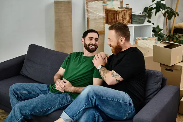 A gay couple is perched atop a couch, sharing a loving moment amidst their relocation boxes in their new home. — Stock Photo