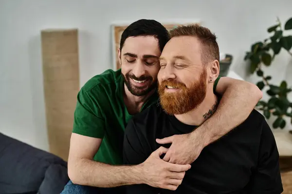 Un moment affectueux entre deux hommes embrassant dans un salon rempli de boîtes mobiles, symbolisant un nouveau départ dans leur nouvelle maison. — Photo de stock