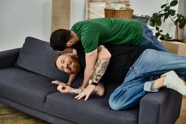 Gay couple lays on a couch in a moment of fun and relaxation, starting a new chapter in their lives. — Stock Photo