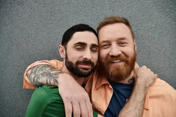 Zwei Männer umarmen sich liebevoll vor einer grauen Wand und drücken ihre tiefe Verbundenheit und Zuneigung zueinander aus. — Stockfoto