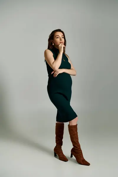 A young pregnant woman exudes elegance in a vibrant green dress as she poses for a portrait. — Stock Photo