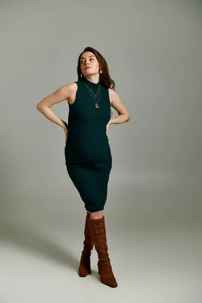 Стильна, вагітна жінка витончено позує в яскраво-зеленому платті, виключаючи елегантність і впевненість. — стокове фото