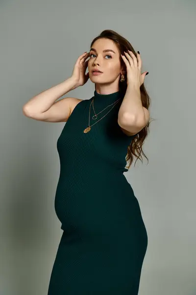 Una giovane donna incinta in un vivido abito verde colpisce una posa, trasudando fiducia e grazia per la fotocamera. — Foto stock