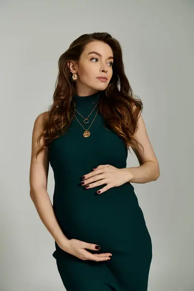 Uma mulher grávida posa elegantemente em um vestido verde vibrante, irradiando alegria e antecipação. — Fotografia de Stock