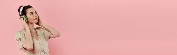 A young pregnant woman in a dress peacefully speaks on her cell phone against a pink background. — Stock Photo