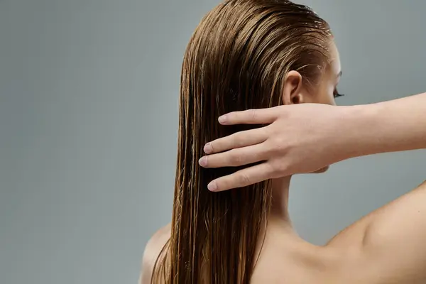 A young woman with long hair is gently touching her wet hair. — Stock Photo