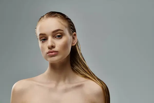 Young woman showcasing her wet hair on a gray backdrop. — Stock Photo
