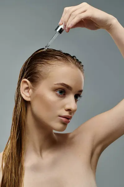 Beautiful woman holding a hair serum, displaying her hair care routine with wet hair. — Stock Photo