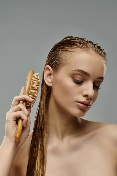 A young woman with wet hair showcases her hair care routine by brushing her long locks. — Stock Photo