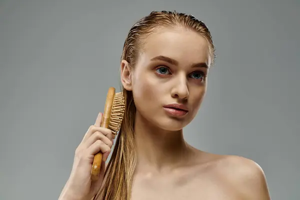 Eine schöne junge Frau demonstriert ihre Haarpflege-Routine mit einem Pinsel in der Hand. — Stockfoto