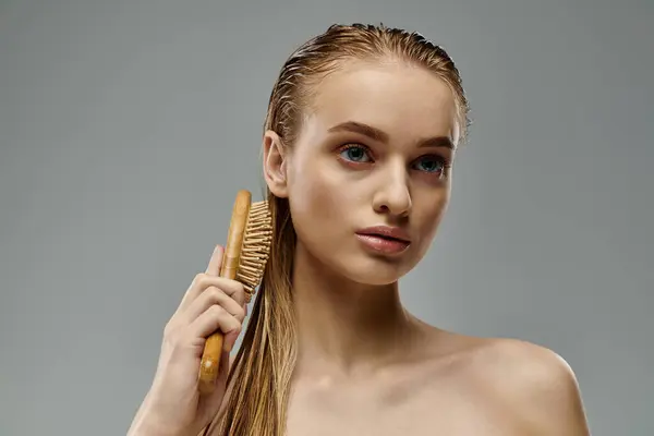A beautiful young woman demonstrating her hair care routine with a brush in hand. — Stock Photo