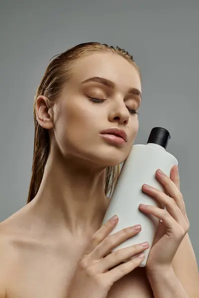 Beautiful woman showcasing hair care with shampoo bottle in hand. — Stock Photo