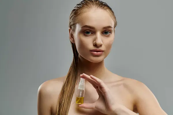 Mulher jovem segura garrafa de óleo de cuidados com o cabelo, promovendo rotina de cabelo saudável. — Fotografia de Stock