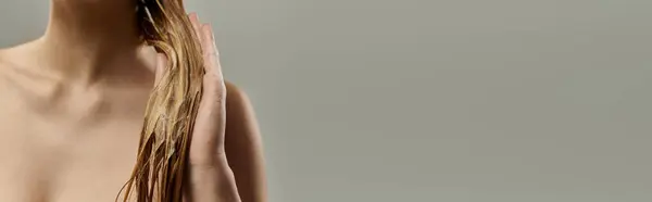A young beautiful woman showcasing her wet long hair against a gray backdrop. — Stock Photo