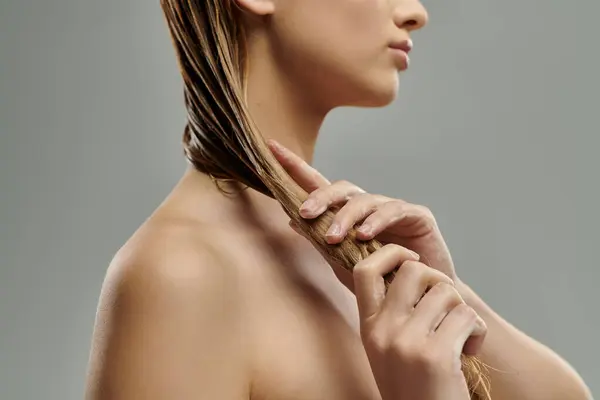 Appealing woman with long hair tenderly applying hair care products. — Stock Photo
