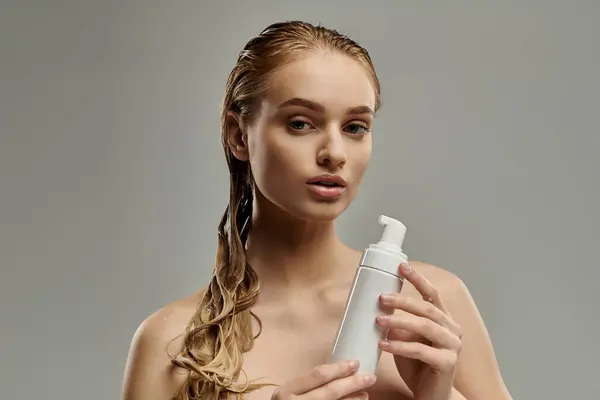 Uma jovem com cabelo molhado segura uma garrafa de loção em suas mãos, mostrando sua rotina de cuidados com o cabelo.. — Fotografia de Stock