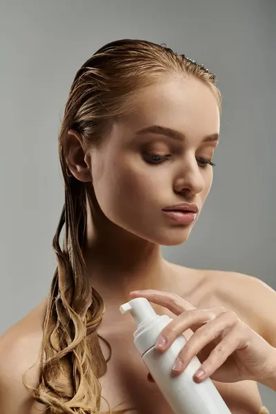 Attractive woman with wet hair holds a bottle of lotion in her hands, showcasing her hair care routine. — Stock Photo