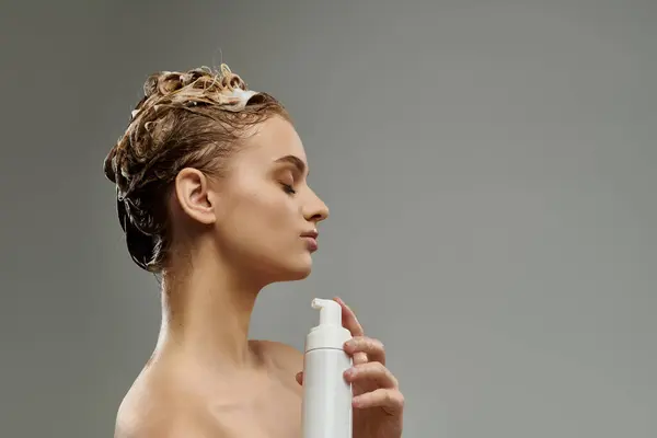 Femme élégante tenant le flacon pulvérisateur, prenant soin des cheveux mouillés. — Photo de stock