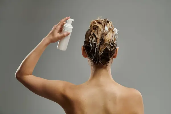 Sophisticated woman applying hair care product and washing hair. — Stock Photo