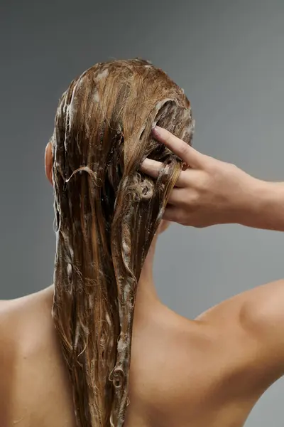 A young beautiful woman demonstrates her hair care routine, washing her hair. — Stock Photo