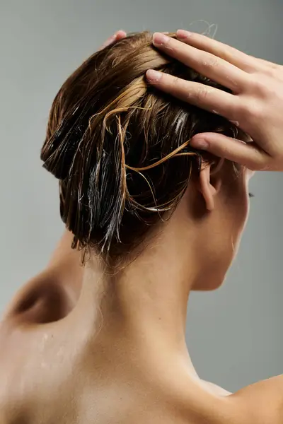 Молодая женщина демонстрирует процедуру ухода за волосами с мокрыми волосами. — стоковое фото
