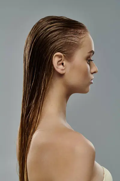 Junge Frau posiert mit nassen Haaren vor grauem Hintergrund. — Stockfoto