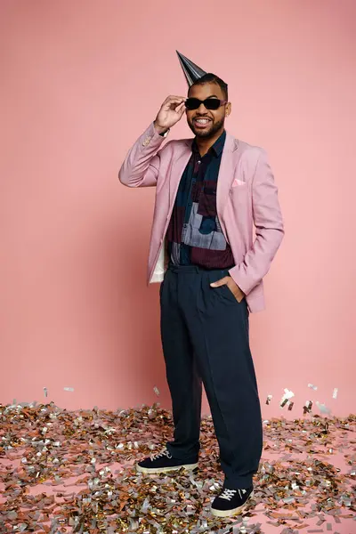 African American man in pink jacket and sunglasses stands in colorful confetti. — Stock Photo