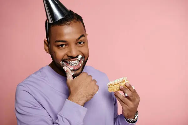 A young, happy African American man in braces smiling while indulging in a piece of cake at a celebration. — Stock Photo