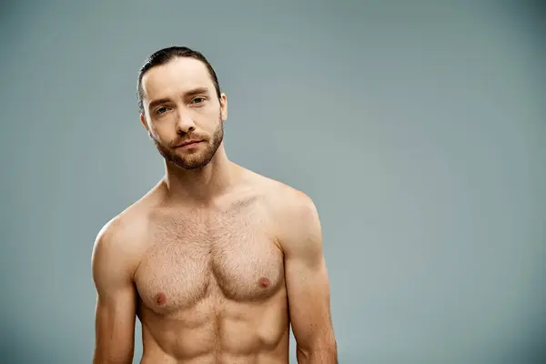 A bearded, shirtless man exudes confidence against a grey backdrop. — Stock Photo