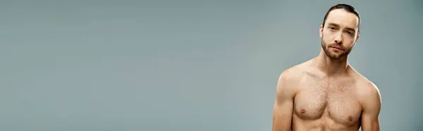 A bearded, shirtless man exudes confidence against a grey studio backdrop. — Stock Photo