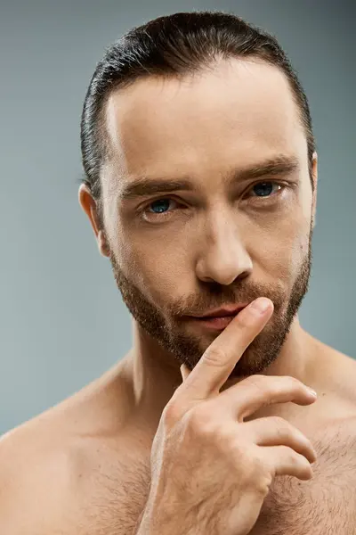 Shirtless, handsome man with beard standing in studio with finger on his nose, showing thoughtful expression. — Stock Photo