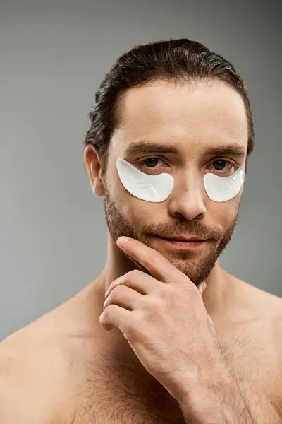 A shirtless man with a beard wearing eye patches, exuding mystery and intrigue in a studio setting against a grey background. — Stock Photo