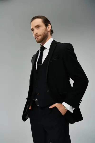 Handsome, bearded businessman in a suit and tie confidently poses in a studio setting against a grey background. — Stock Photo