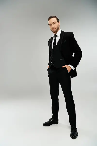 A bearded businessman in a sleek tuxedo poses confidently against a grey studio backdrop. — Stock Photo