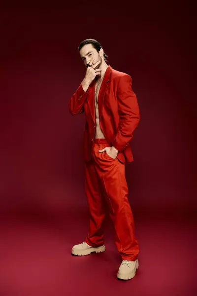 Un bel homme en costume rouge pose en toute confiance sans chemise dans un décor de studio. — Photo de stock