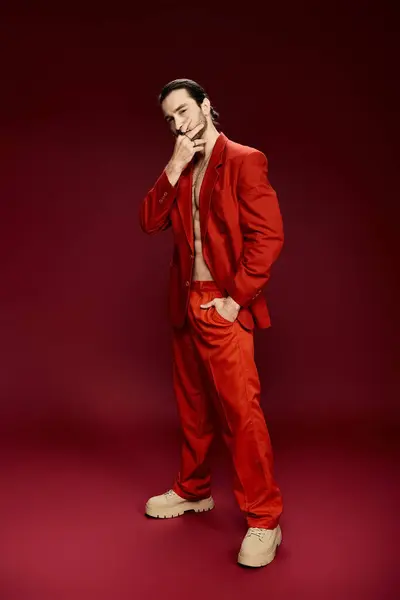 A handsome man in a red suit poses confidently without a shirt in a studio setting. — Stock Photo