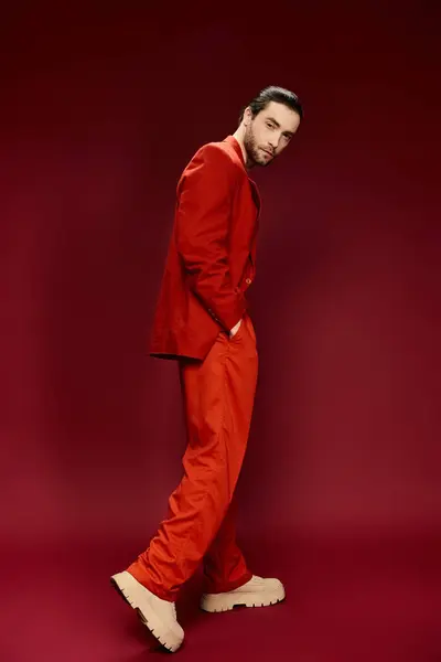 A stylish man with a red suit and no shirt striking a pose in a studio setting. — Stock Photo